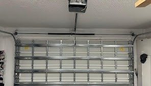 Closed ribbed steel garage door with an opener unit mounted on the ceiling above it