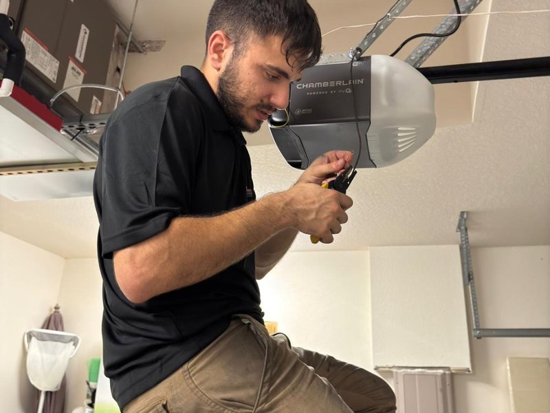 Technician working on a garage door opener mounted to the ceiling