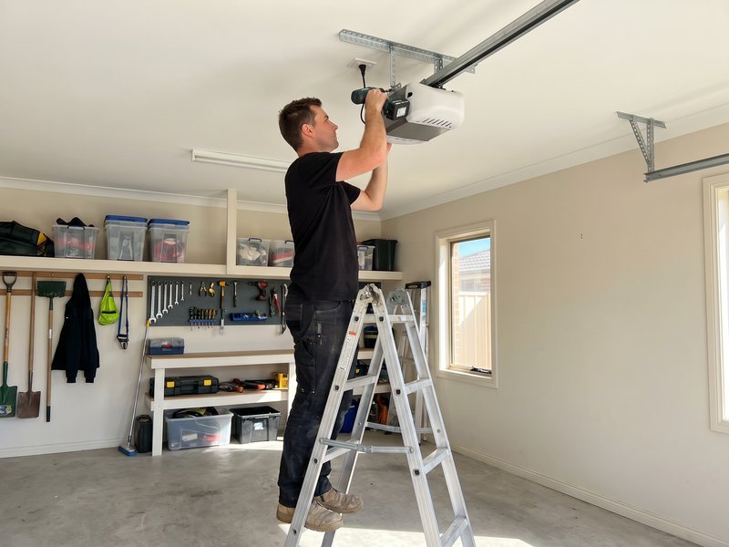 Technician on a ladder mounting an opener rail to the ceiling