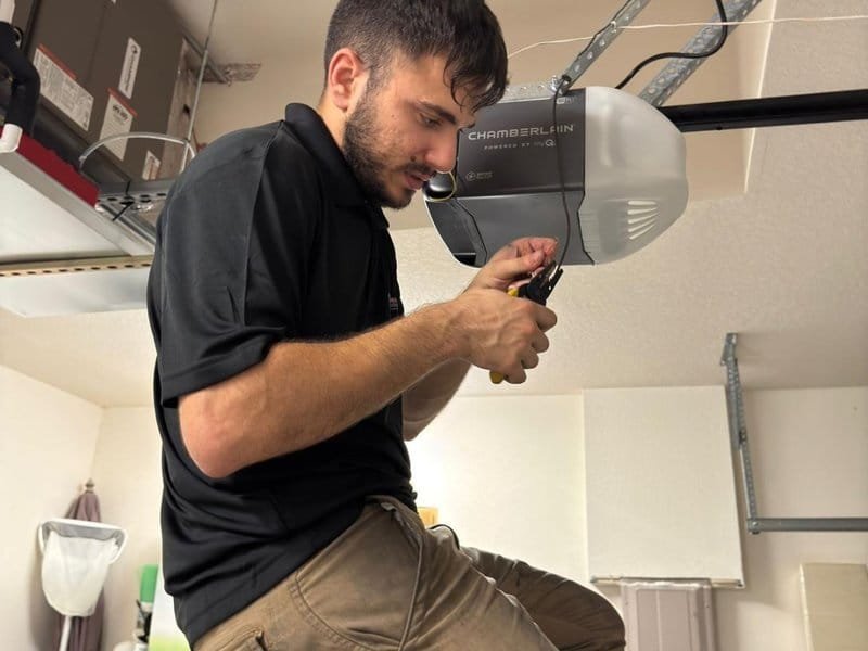 Technician holding a tool against a ceiling-mounted opener head