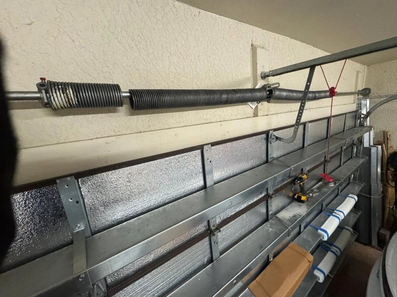 Torsion spring with a center bracket mounted above the top of an insulated garage door