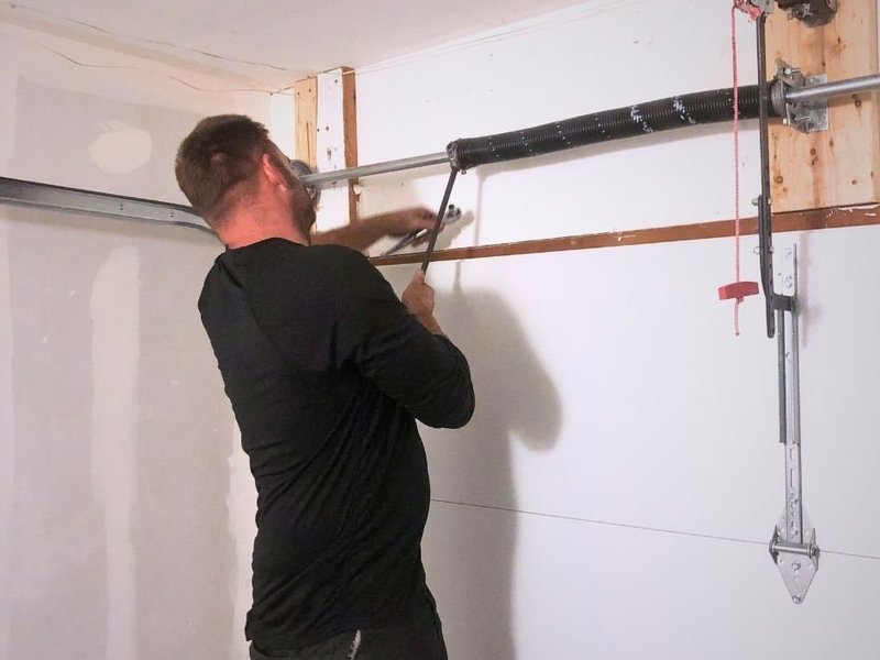 Technician working at the torsion spring above a garage door